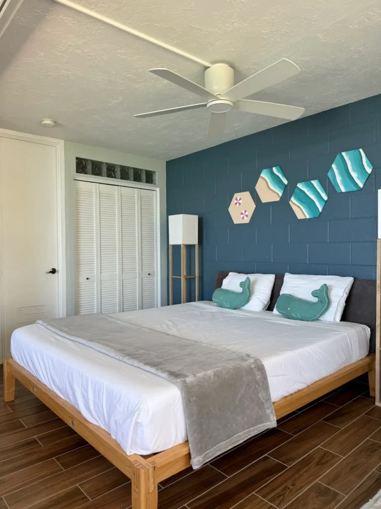Modern bedroom with California king bed and handmade ocean-inspired artwork in an oceanfront condo on Oʻahu’s North Shore, Hawaii.