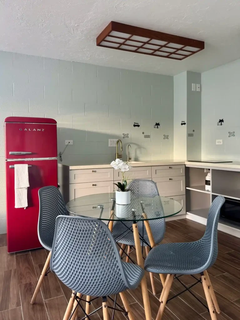 Bright modern kitchen and dining area in an oceanfront Hawaii condo with red vintage-style refrigerator and open island atmosphere.