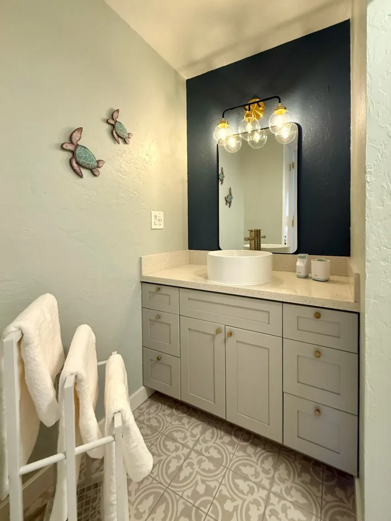 Modern retro bathroom with patterned tiles and Hawaiian wall decor inside an oceanfront condo on Oahu.