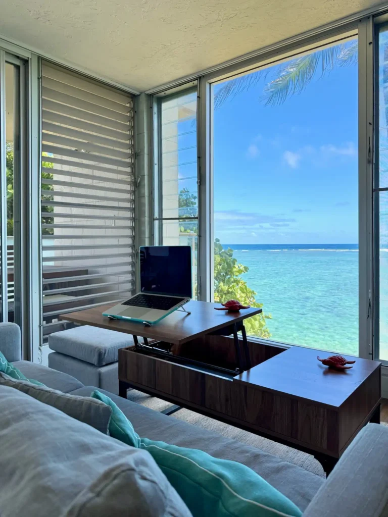 Oceanfront remote workspace with laptop and panoramic ocean views in a beachfront apartment on Oʻahu, Hawaii